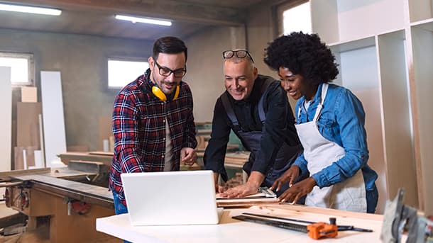 three carpenters looking at a laptop